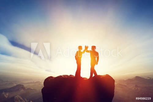 Two men, friends high five on top of the mountains. Agreement