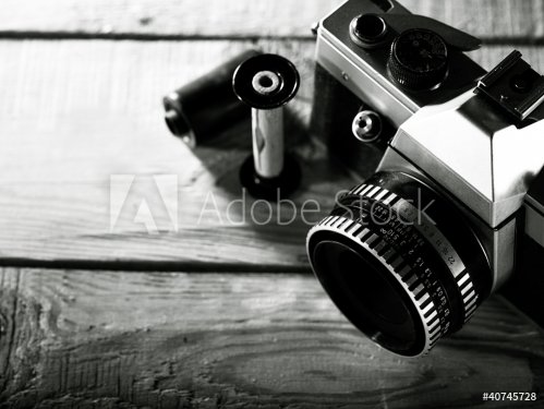 Vintage 35 mm film photo camera over wooden desk - 900463782