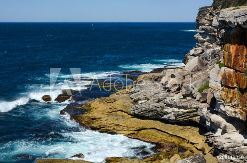 Waves crashing against rugged rock coastline at Lady Bay in South Head, NSW, Australia