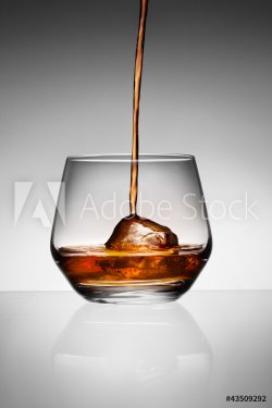 Whisky pouring on ice in glass. - 900671687