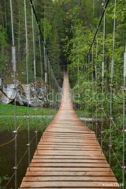 Wooden suspension bridge over the river in the forest - 901147957
