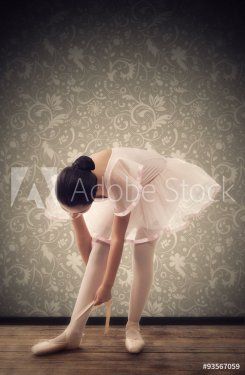 Young Ballerina while tying ballet shoes