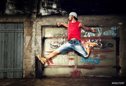 Young man jumping, dancing on grunge wall