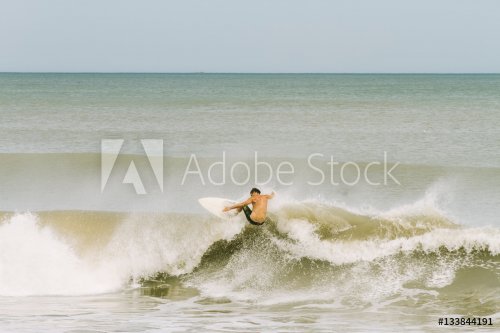 Young man surfing a wave on the shores of Mar del Plata, Argentina