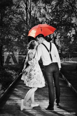 Young romantic couple in love flirting in rain. Red umbrella