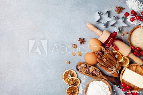 Bakery background with ingredients for cooking christmas baking decorated with fir tree. Flour, brown sugar, eggs and spices on kitchen table top view.