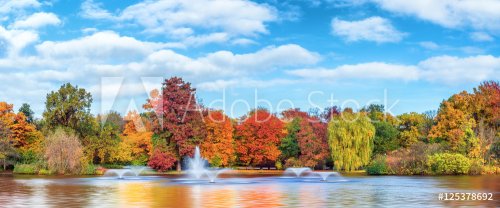 Beautiful fall landscape and cloudy sky. Autumn panorama - yellowed trees in city park in cloudy weather. Pond with fountains in South Park, Wroclaw Poland. 
