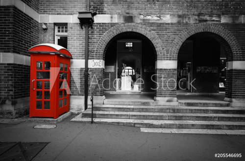 Black and white street scene with selective color on a red phone box in Sydney, Australia