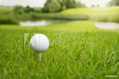 Golf ball on a tee against the golf course with copy space - 900453033
