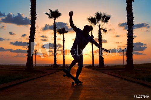 man riding on skateboard near the ocean in sunset - 901144445