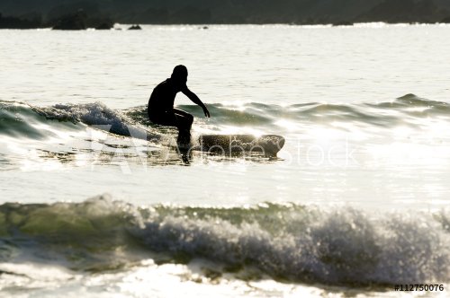 surfer man silhouette in solitary beach with  flat sea at sunset , selective focus