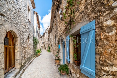 A typical narrow, winding alley with French Bleu shutters in the medieval village of Tourrettes Sur Loup, France.
