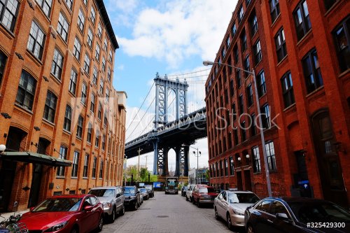 Manhattan bridge seen from a red brick buildings in Brooklyn street in perspective, New York, USA.