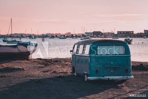 A vintage camper van parked near the sea at sunset
