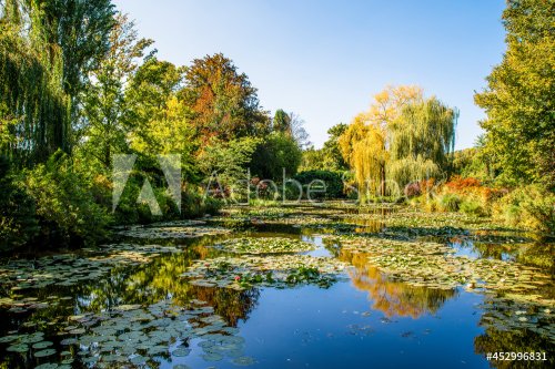 Le célèbre pont japonais de Monet est vu de l'autre côté d'un étang dans ses jardins à Giverny, en France, par une belle journée ensoleillée.