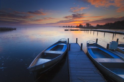 Peaceful sunrise with dramatic sky and boats and a jetty - 900143938