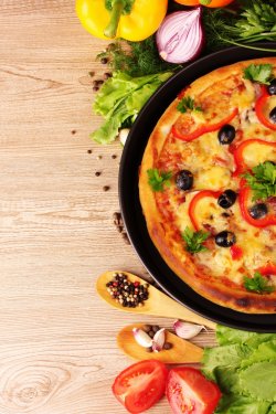 tasty pizza on the plate and vegetables on a wooden background - 900210775