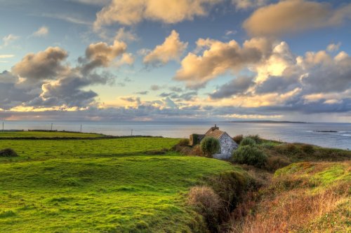 Irish cottage house near the ocean at sunset - 900226449