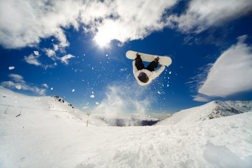 Snowboarder going off jump doing a backflip