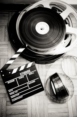 Movie clapper board and film reel on wooden floor - 901145175