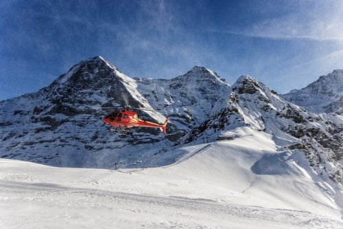Red helicopter landing at swiss ski resort near Jungfrau mountai - 901145614
