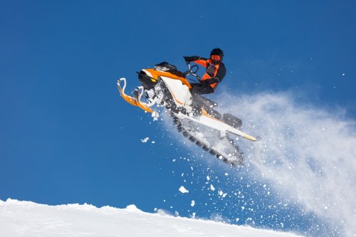 the guy is flying on a snowmobile on a background of blue sky leaving a trail... - 901151578
