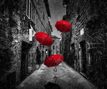 Umrbellas flying with wind and rain on dark street in an old Italian town in Tuscany, Italy