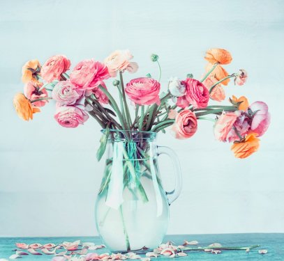 Lovely bouquet of beautiful Ranunculus flowers in glass vase on table at light blue turquoise background, pastel color