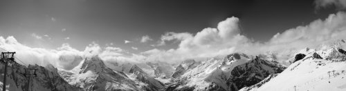 Black and white panorama of ski slope and snowy mountains