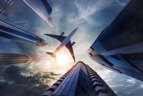 Low angle view of airplane above skyscrapers - 901156634
