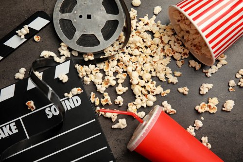 Flat lay composition with popcorn, film reel and clapperboard on grey background