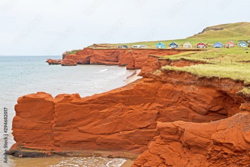Eroded red sandstone cliffs and colorful cottages are typical of landscapes a... - 901157719