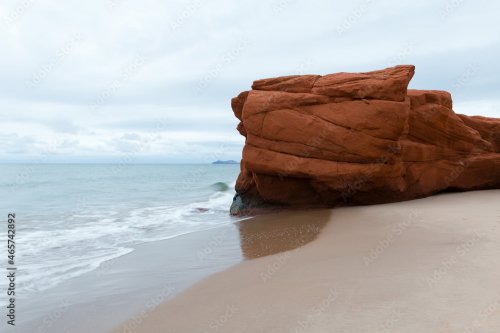 Horizontal view of red sandstone cliff on Dunes-du-Sud beach, with the Entrance Island in soft focus background, Havre-aux-Maisons, Magdalen Islands, Quebec, Canada