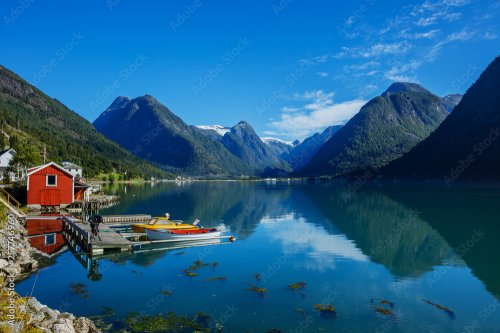 Belle maison de pêche rouge sur le fjord. Nature avec ciel bleu, reflet dans l'eau et maison de pêche en Norvège