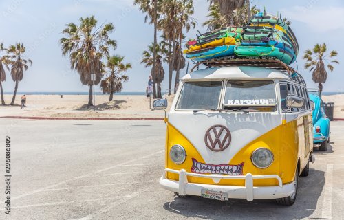 Surf boards stacked on a yellow van roof, sunny spring day. Venice beach, California USA.