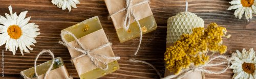 Top view of homemade soap bars, candle and dry chamomiles on wooden surface - 901158194