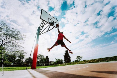 Street basketball player making a powerful slam dunk on the court - 901158306
