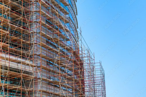 Modern building is under construction, metal scaffolding - 901158430