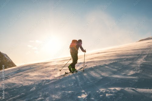 Man skier with backpack trekking on snow mountain with sunlight